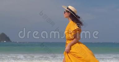 下午，穿着黄色衣服和草帽的年轻女子在沙滩上散步，<strong>心情舒畅</strong>