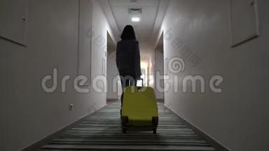 一个年轻的女孩带着一个手提箱沿着<strong>酒店</strong>走廊走。 入住<strong>酒店</strong>.. 从后面看。 4k决议