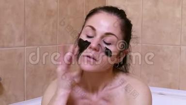 女人在洗澡时把黑色<strong>洁面乳面</strong>罩涂在脸上。 皮肤护理概念