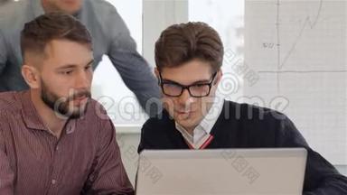 四位年轻的创意经理看着办公室里的笔记本电脑