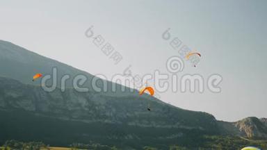 在阿尔卑斯山上空飞行的橙色护墙。滑翔伞在阿尔卑斯山的蓝天和高山上飞行。滑翔伞课程