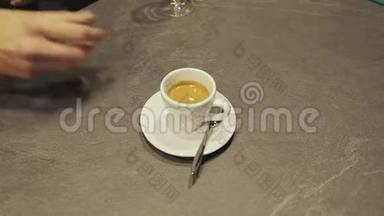 手的特写，放置热的陶瓷白色咖啡杯与烟雾在茶托在桌子上。 提供咖啡杯