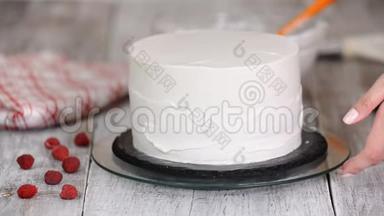 一步一步。 女人`手在海绵蛋糕上撒鲜奶油。 面包师用抹刀用奶油准备蛋糕。