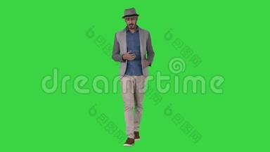 时尚、时尚、积极、开朗的男士穿着休闲衬衫，戴着遮阳帽，在绿色屏幕上与摄像机交谈