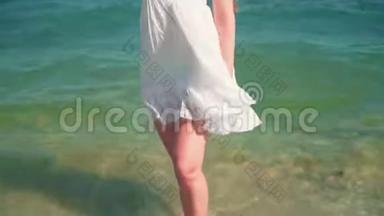 一个穿着白色海滩礼服的女孩站在海边。 一个光着脚的漂亮女孩站在海边。
