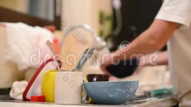 一个女人从一堆脏盘子里拿出一个盘子，洗了它。 把重点放在有脏盘子的前台