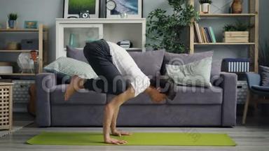 一个英俊的亚洲人<strong>独自在家</strong>做瑜伽练习时倒立