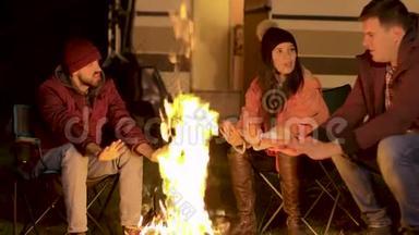 在一个寒冷的秋夜，朋友们在篝火旁暖暖手的手持镜头