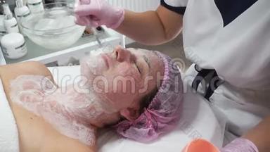 美容师用刷子在成年妇女脸上涂抹<strong>洁面乳</strong>