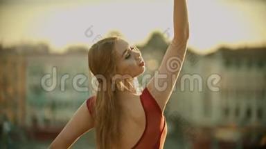年轻优雅的微笑女子芭蕾舞演员在日落时训练她在屋顶上跳舞
