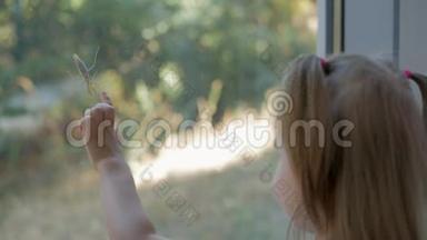 小女孩好奇地看着坐在玻璃门上的螳螂蚂蚱。