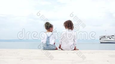 快乐的孩子们，一个小男孩和一个女孩，哥哥和姐姐坐在<strong>海边</strong>，看着一艘<strong>帆船</strong>