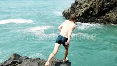 人从悬崖上缓慢地跳入大海。 在暑假玩得开心。