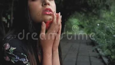 一个西班牙黑发女孩的肖像，手里拿着一个压扁的普通话，脸上涂着普通话。 4k. 4k视频
