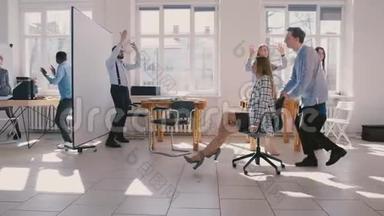慢动作，有趣，兴奋的女商人骑着椅子沿着大办公室庆祝在多民族工作场所的晋升。