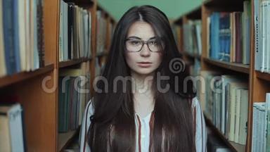 图书馆里漂亮女孩的肖像，留着长长的黑发。 女学生在一大堆书<strong>中学</strong>习