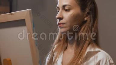 艺术家的肖像。 女孩站在画架上，画了一幅画，她很感兴趣。 4K慢慢