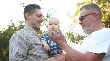 老灰头发的父亲，他英俊的儿子和可爱的孙子的肖像。 祖父教蹒跚学步的孩子拍手