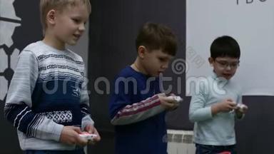在儿童锦标赛`，三个可爱的孩子玩<strong>高科技</strong>游戏，用游戏操纵杆控制机器人，特写镜头