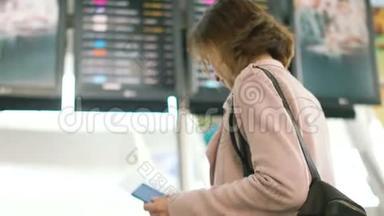 女孩用航班时刻表检查她的机票。 在航班时刻表前一位女士的肖像