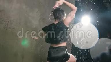 现代舞湿了舞台上雨中的年轻女子。 湿漉漉的舞女舞女在工作室里围着自己转