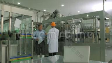 高级经理与机械工人检查生产计划与瓶子生产线在后台。