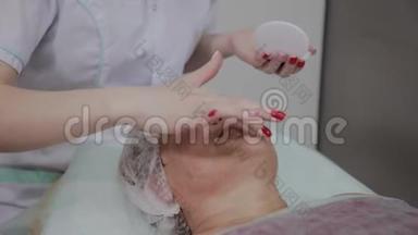 专业美容师对美容院的老年妇女使用保护霜。
