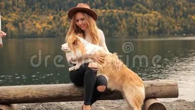 有趣的年轻女人带着狗边界牧羊犬在湖边<strong>遇见</strong>了女朋友。 在山脉的背景上。
