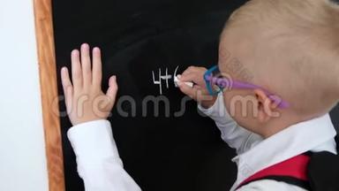 可爱的小男孩<strong>在黑板上写字</strong>。 带包的小学孩子。 教育观念。 回学校去。