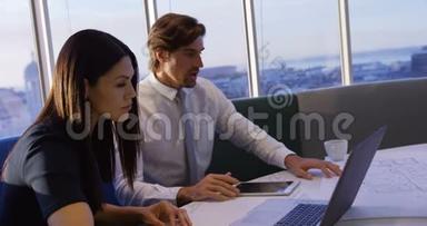 白种人年轻的办公室<strong>管理人</strong>员在办公室4k的桌子上使用笔记本电脑和蓝图