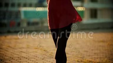 站在屋顶上穿着红色裙子的年轻女子芭蕾舞女演员-用手跳舞-明亮的日落