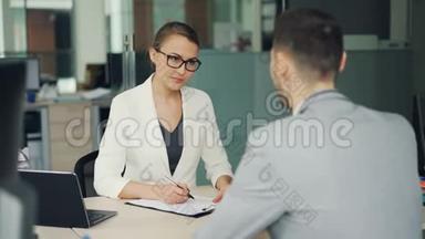 美女招聘人员在办公室面试时和男应聘者聊天，女应聘者在做笔记然后发抖