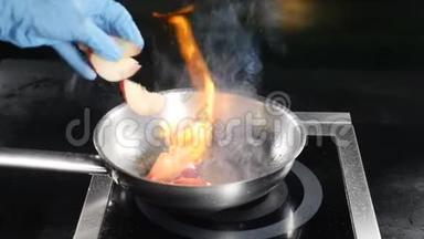 食品<strong>视频</strong>概念。 厨师戴着蓝色手套，在餐厅厨房煮火焰菜。 把切好的<strong>桃子</strong>放在火里