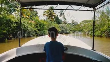 小快乐船长男孩在狩猎之旅船前航行，沿着田园诗般的异国丛林河与郁郁葱葱的绿色植物。