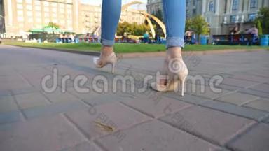 镜头跟随苗条的女腿穿着高跟鞋穿过城市街道。 穿高跟鞋的年轻女子脚