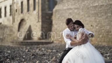 在<strong>城堡</strong>附近的石岸上观看充满爱的时尚新娘和新郎的户外照片。 行动。 漂亮的<strong>婚礼</strong>情侣