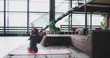 有魅力的运动女士在家里练习瑜伽，在客厅的垫子上，她做瑜伽姿势，倒立