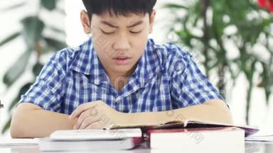 亚洲男孩在前面的家庭<strong>作业</strong>生气，男孩在家里做你的家庭<strong>作业</strong>生气的脸在家里。