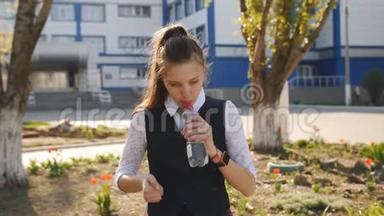 穿校服的女学生从学校附近的塑料瓶里喝水。