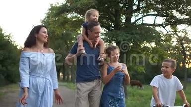 年轻的父亲和母亲带着他们的三个孩子走在田里的路上。<strong>全家</strong>暑假快乐