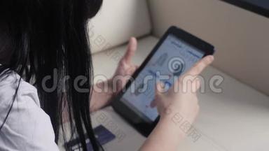 女孩用数码平板电脑打造网购概念。黑发女人躺在沙发上看网上生活用品店