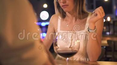 在夜店吃甜点的年轻女子。美丽的女人在优雅的餐厅里用玻璃杯喝红酒。