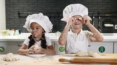 孩子们在私人厨房里一起玩烹饪。 儿童厨师概念。 桌子上有面团、面粉和擀面杖