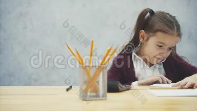 年轻的，头发硬的女孩坐在桌子旁。 在这题词的手<strong>中考</strong>试.. 看上去很糟糕。