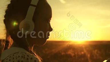 女孩梦想在阳光下音乐。 少女听音乐看日落。 快乐的女孩跳舞