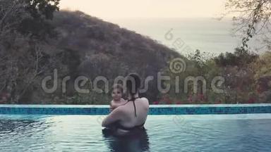 在丛林无限的游泳池里拍摄妈妈和宝宝的空中镜头。