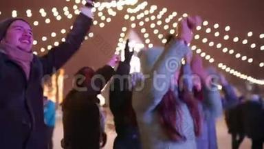 年轻人在城市广场的圣诞音乐会上聚会。 朋友们用举手和跳舞的方式跳得很开心
