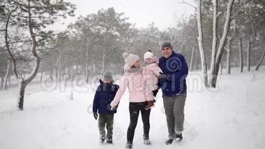 友好的<strong>全家</strong>人在降雪的情况下在冬天的森林里散步。 父亲、母亲、儿子和女儿