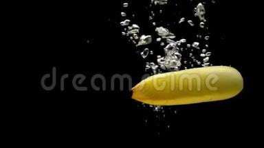 两根黄色的香蕉在黑色的背景下落入透明的水中