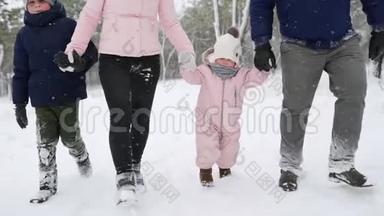 穿着暖身连衣裙的宝宝在做第一步。 孩子学会走路。 友好的全家人在冬季森林散步度假